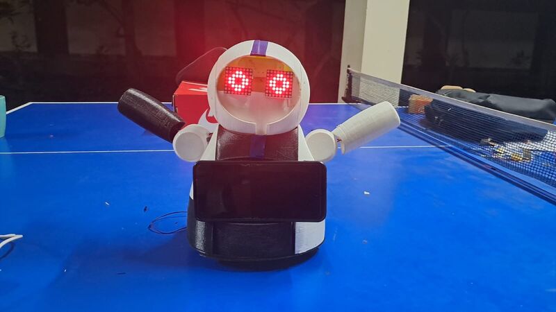 The finished joyRobot: white and black rounded body, red LED-matrix eyes lit, a phone mounted on its chest as a screen