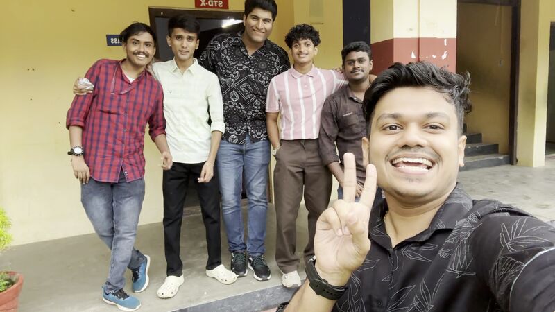 The six-person college team taking a selfie outside a classroom at the school — no students in frame