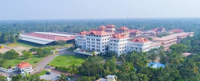 The Amritapuri campus of Amrita Vishwa Vidyapeetham — buildings between palms, backwaters behind